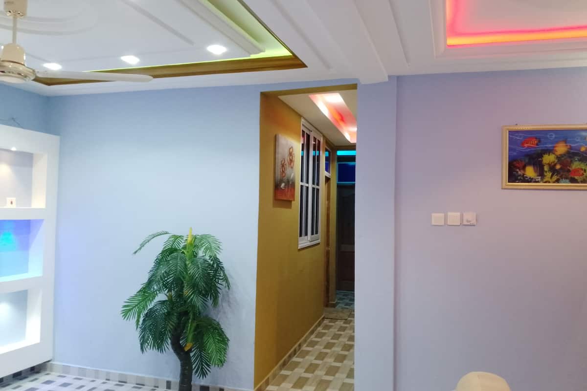 A hallway with a ceiling fan, a potted plant, a painting, and a tiled floor.