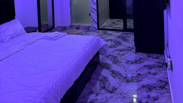 Ein modernes Schlafzimmer mit Bett, begehbarem Kleiderschrank und einem Badezimmer mit Duschkabine.