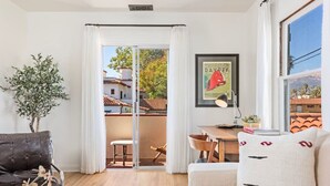 Un salon moderne doté d’une porte-fenêtre coulissante donnant sur un balcon, d’un canapé, d’une table basse et d’un tableau encadré accroché au mur.