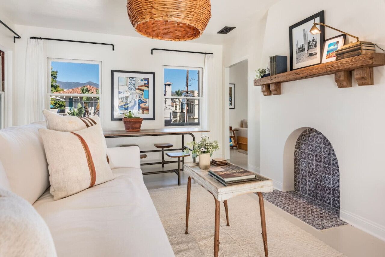 A living room with a sofa, a coffee table, a hanging basket, and a fireplace.