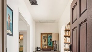 A hallway with a wooden door, a cabinet with drawers, a rug, and a framed picture on the wall.