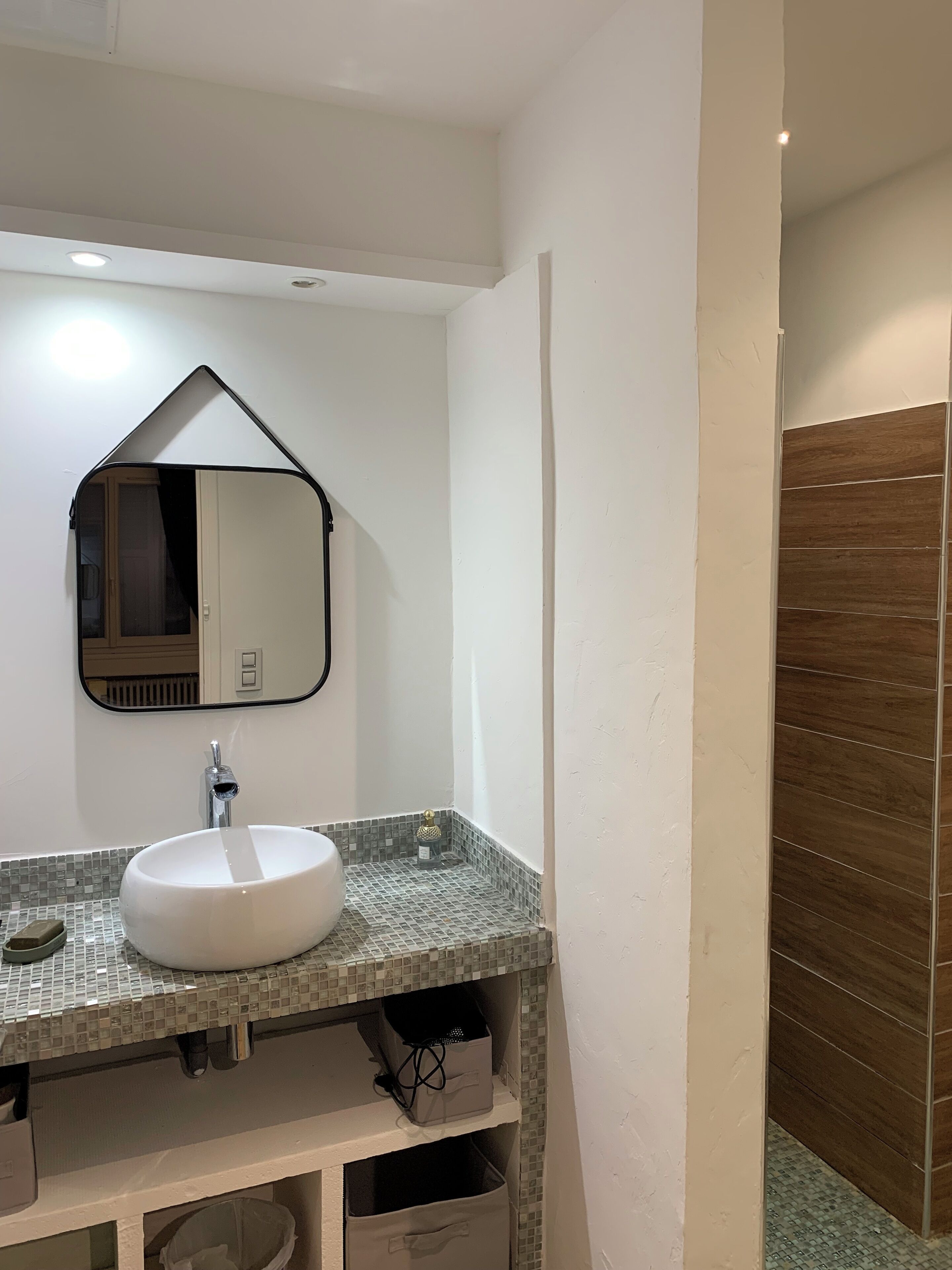 A bathroom with a white sink, a mirror with a black frame, and a tiled backsplash.