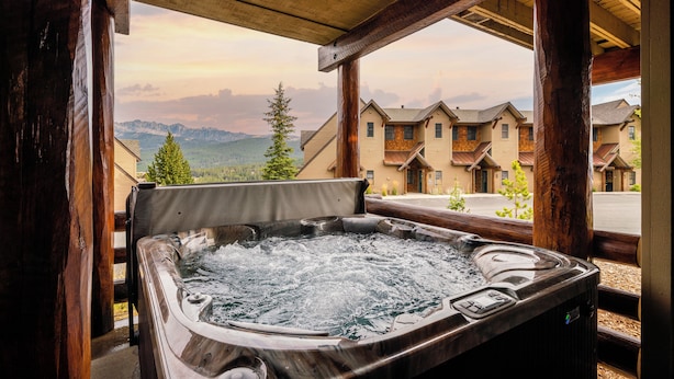 Un bain à remous avec vue sur les montagnes et un chalet en arrière-plan.