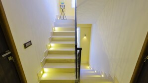 A staircase with white steps and black railings, leading to a landing with a water dispenser. - Hazee Beach Stay (Tirukalukundram)