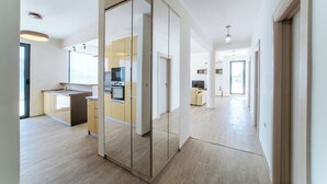 Eine moderne Küche mit einer zentralen Kochinsel, ein Essbereich mit einer Couch und ein Flur, der zu weiteren Räumen führt.