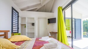 Habitación de hotel con dos camas, televisión, escritorio y balcón con vistas al exterior.