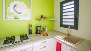Una cocina con estufa a gas, cafetera y una piña en la encimera.
