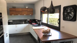 Una cocina moderna con armarios blancos, encimera de madera y un ventanal grande.