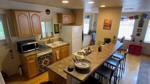 A kitchen with wooden cabinets, a microwave, a sink, a stove, and a dining area with bar stools.