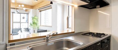 A modern kitchen with a stainless steel sink, a stove, and a black marble cabinet.