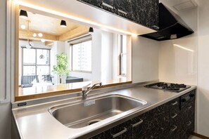 A modern kitchen with a stainless steel sink, a stove, and a black marble cabinet. - SLEEPLAB THE STAY Casual Shinjuku (Tokyo)