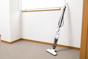 A vacuum cleaner in a corner of a room with a wooden baseboard and a white wall. - SLEEPLAB THE STAY Casual Shinjuku (Tokyo)