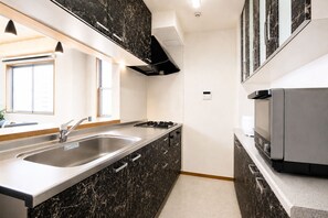 A modern kitchen with a stainless steel sink, black marble countertops, and a built-in microwave. - SLEEPLAB THE STAY Casual Shinjuku (Tokyo)
