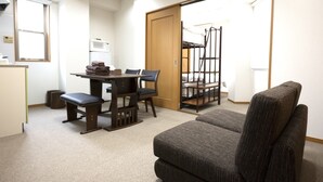 Une pièce de taille modeste comprenant une table à manger, des chaises, un canapé, une armoire et un lit avec une échelle.