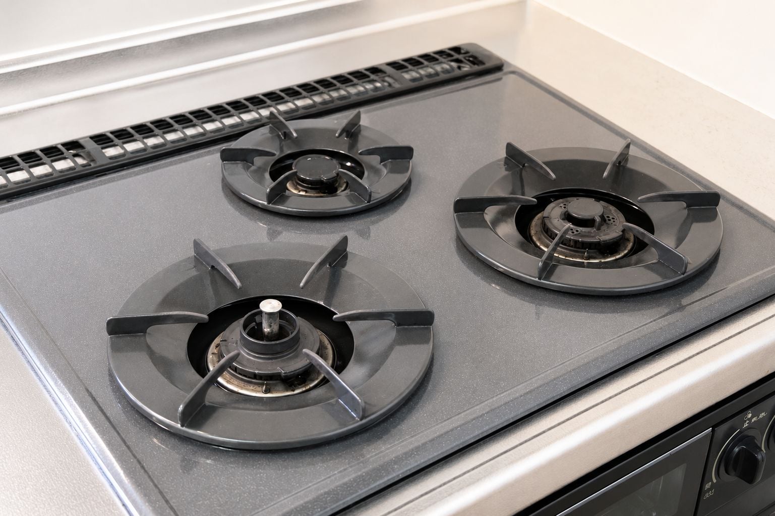 A kitchen stove with three burners and a vent hood.