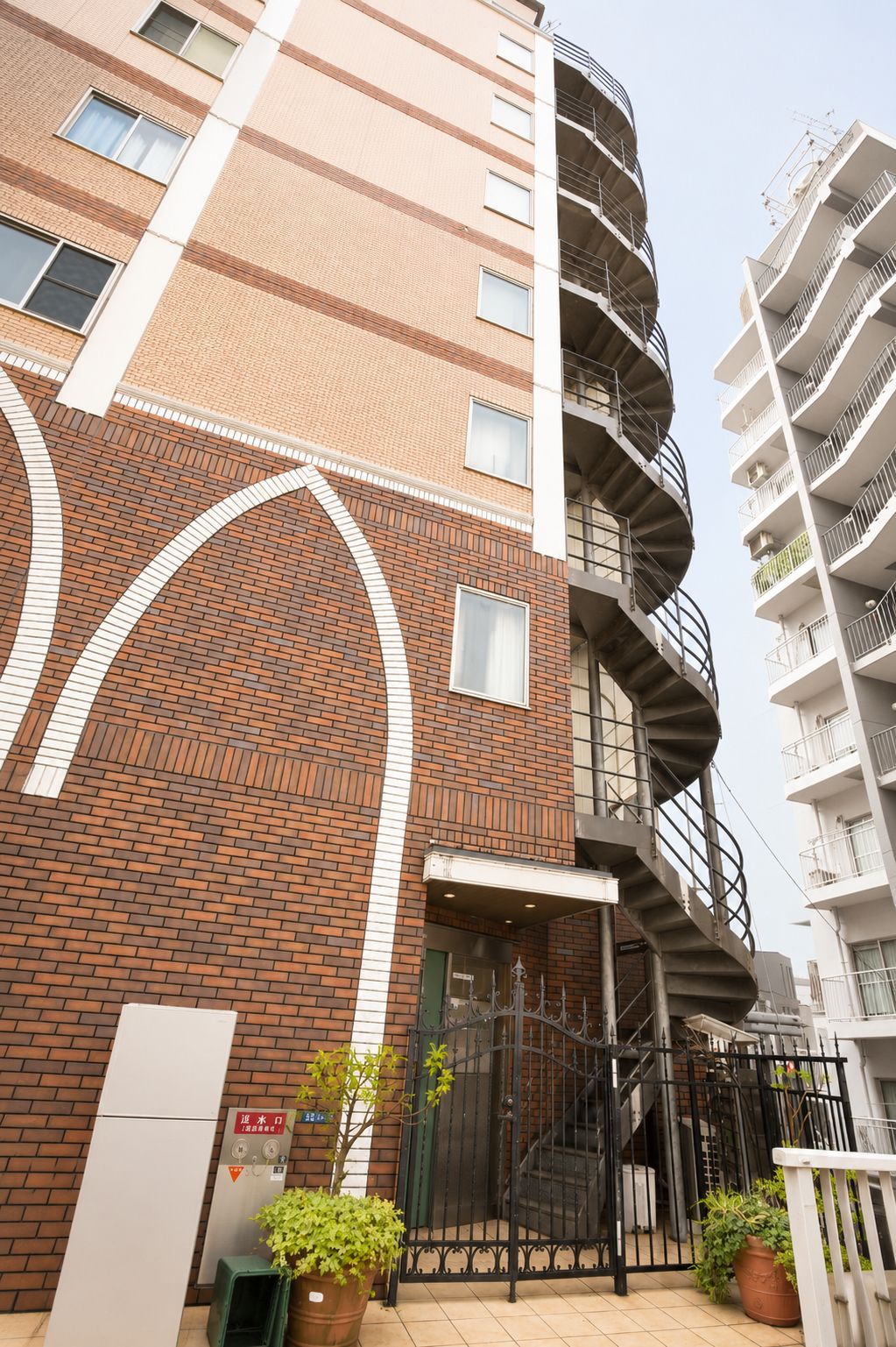 Un immeuble résidentiel à plusieurs étages, doté d’une façade en briques, d’un escalier en colimaçon et d’une entrée sécurisée par un portail.