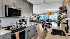A modern kitchen with grey cabinets, a built-in microwave, and a large island with a sink. - Horizon Haven•Hot Tub•Views•Game Room•Speakeasy (Tucson)