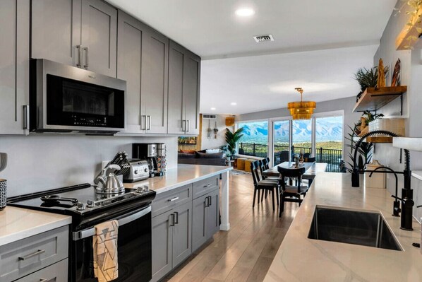 A modern kitchen with grey cabinets, a built-in microwave, and a large island with a sink.