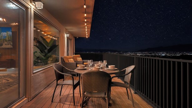 A deck with wicker furniture and a table set for dining, overlooking a night sky with stars and a cityscape. - Horizon Haven•Hot Tub•Views•Game Room•Speakeasy (Tucson)