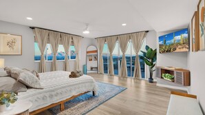 A spacious bedroom with a large bed, a view of the sea, and a ceiling fan. - Horizon Haven•Hot Tub•Views•Game Room•Speakeasy (Tucson)