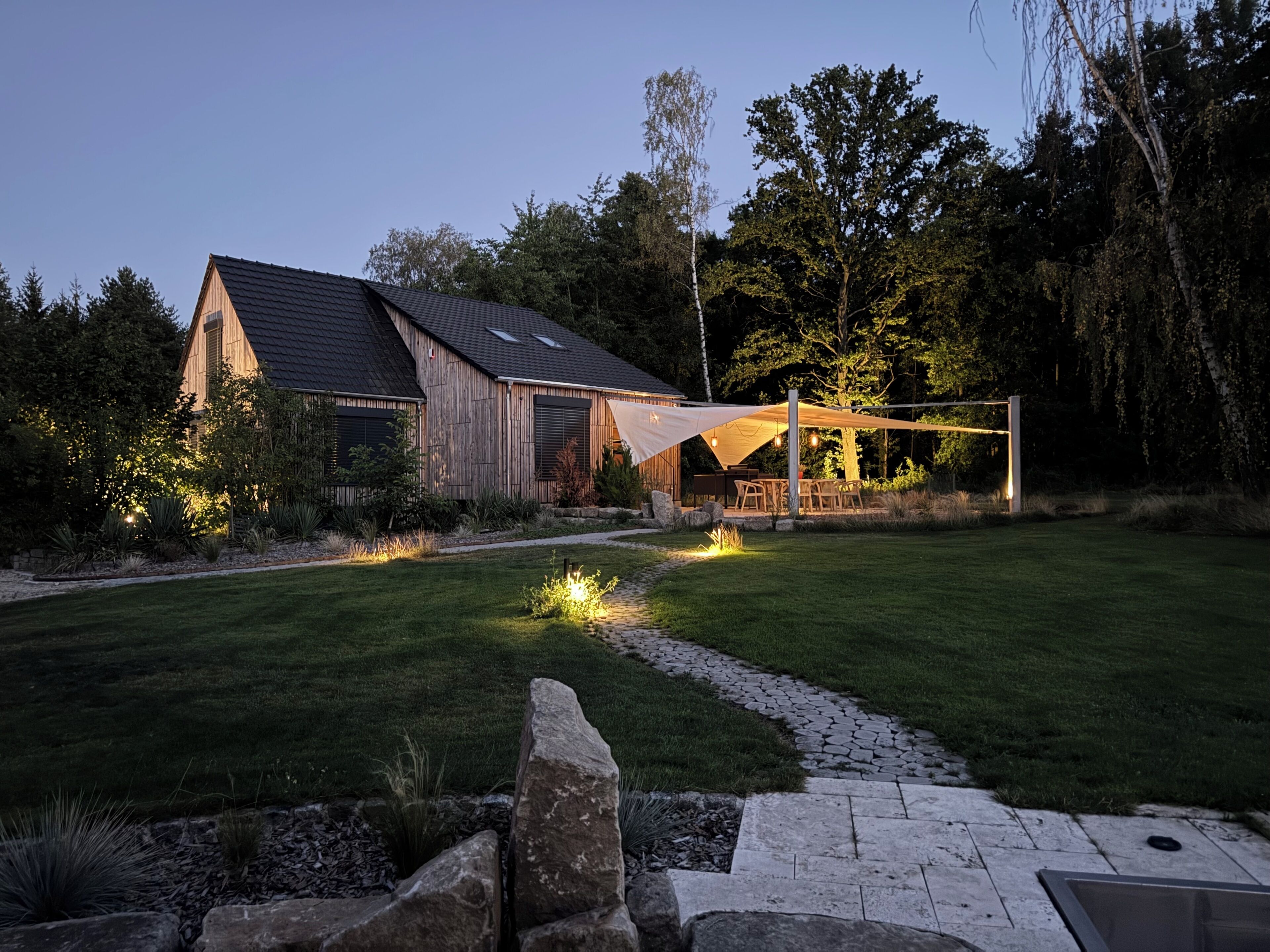 A wooden house with a sloped roof and a covered outdoor seating area.
