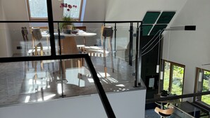 Una cocina moderna con una isla grande, un comedor con mesa y sillas, y vista a un jardín a través de ventanales amplios.