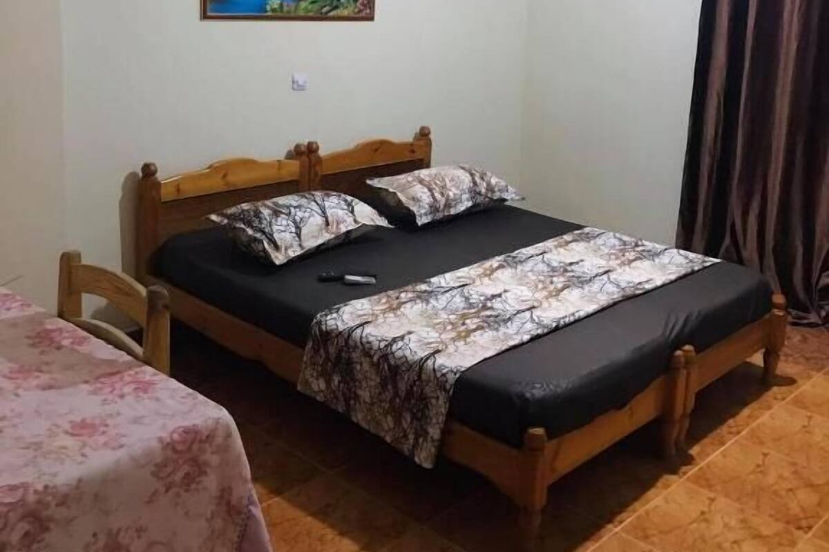 A bedroom with a bed, a chair, a table, and a painting on the wall.