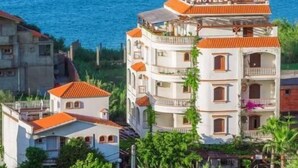 Un hôtel à plusieurs étages, doté d’un toit recouvert de tuiles rouges, de balcons et d’une enseigne indiquant qu’il s’agit d’un hôtel.