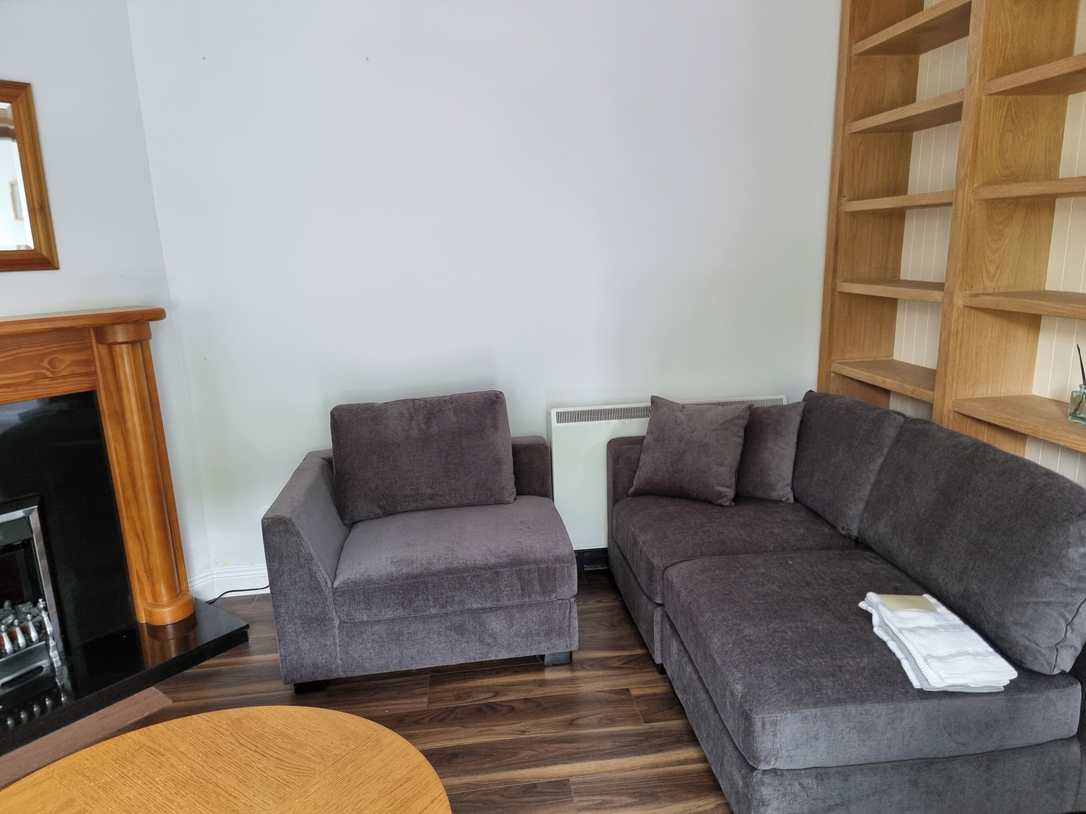 A living room with two grey sofas, a wooden coffee table, a fireplace, and a white radiator.
