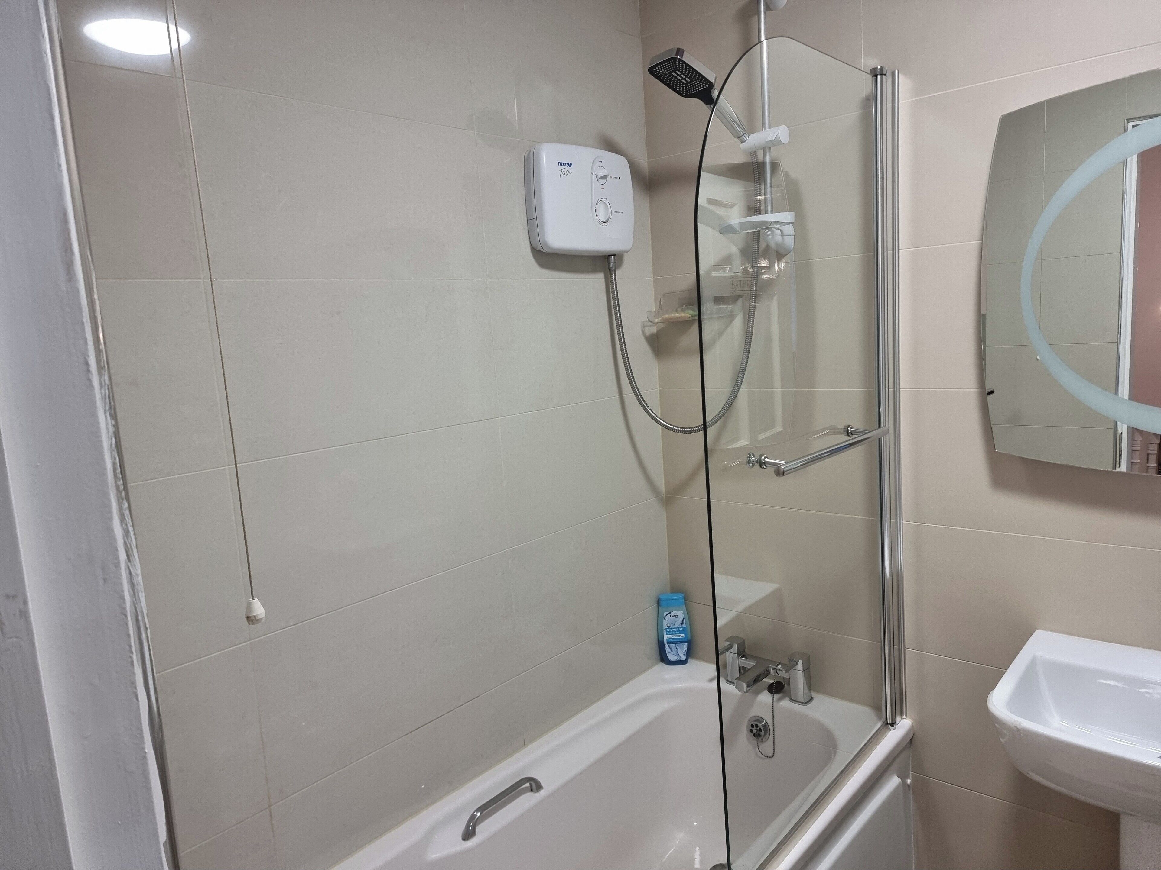 A modern bathroom with a glass-enclosed shower, a white bathtub, and a sink.
