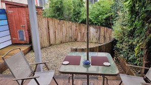 A patio with a table and two chairs, surrounded by a wooden fence and greenery. - 3-beds, Sleep 7 With Garden & Private Parking (Carrick-on-Shannon)