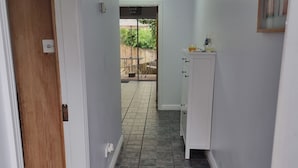 A hallway with a wooden door, white cabinets, a tiled floor, and a view to an outdoor patio area. - 3-beds, Sleep 7 With Garden & Private Parking (Carrick-on-Shannon)