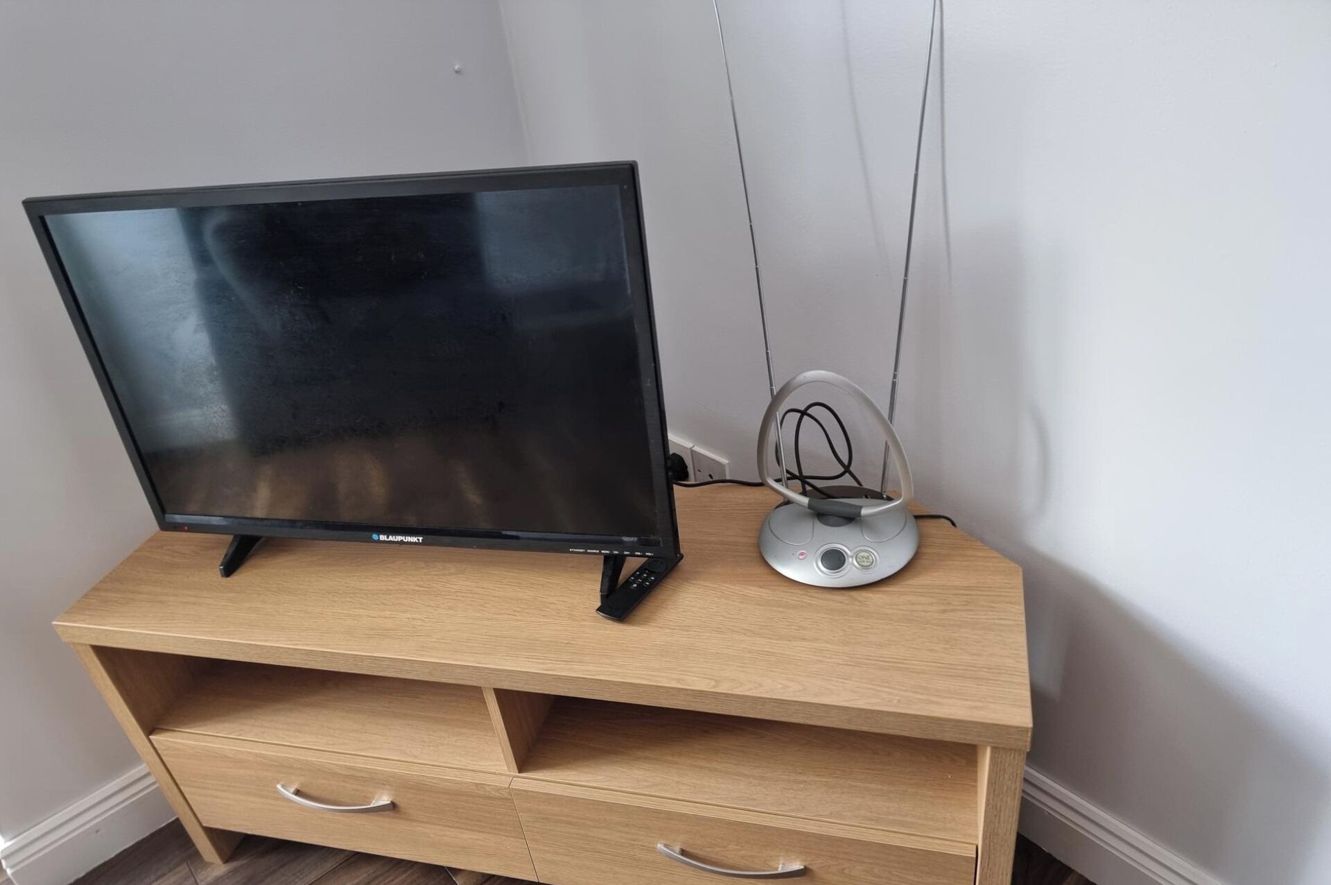 A wooden TV stand with a flat-screen TV and a small speaker.