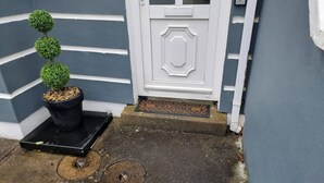 A house entrance with a white door, a small potted plant, and a doormat. - 3-beds, Sleep 7 With Garden & Private Parking (Carrick-on-Shannon)