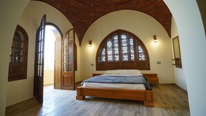 Ein Schlafzimmer mit einem hölzernen Bett, gewölbten Fenstern und einer Ziegeldecke.