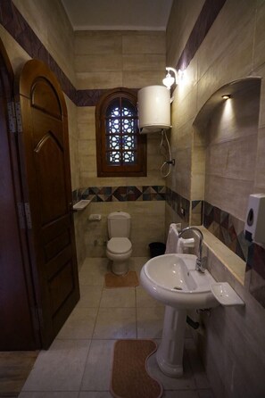 A bathroom with a toilet, sink, and a window with a decorative grille. - Tunis castle  (Yusuf as-Sidiq)