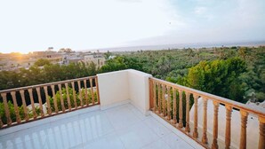 Ein Balkon mit Fliesenboden und Holzbalkonen, mit Blick auf Stadtlandschaft und üppiges Grün.