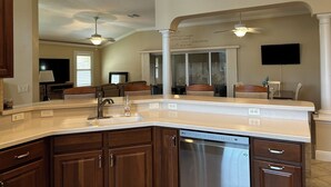 A modern kitchen with a built-in dishwasher, a large mirror, and a ceiling fan. - Upgraded 3:2 House in Amelia mins to Sumter Landing, golf & pool. New rental. (The Villages)