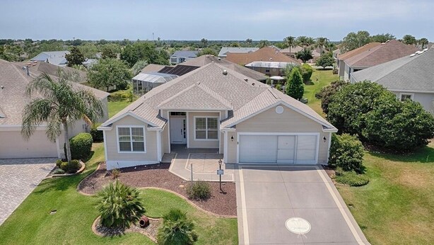 A single-story house with a garage, a front yard with a small tree, and a clear sky. - Upgraded 3:2 House in Amelia mins to Sumter Landing, golf & pool. New rental. (The Villages)