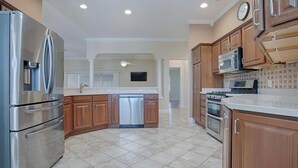 A modern kitchen with stainless steel appliances, wooden cabinets, and a tiled floor. - Upgraded 3:2 House in Amelia mins to Sumter Landing, golf & pool. New rental. (The Villages)