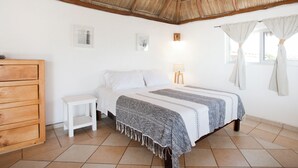 A bedroom with a bed, a nightstand, a wooden dresser, a window with curtains, and a thatched roof ceiling. - Charming rooftop bungalow 1 block from the beach! (Corral del Risco)