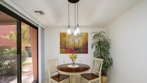 A dining area with a round table, four chairs, a vase with flowers, and a painting on the wall. - CASA FAMILIA - 1st floor 2-bedroom unit (Phoenix)