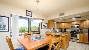 Una cucina moderna con mobili in legno, elettrodomestici in acciaio inossidabile e un'area pranzo con tavolo e sedie in legno.