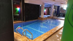 An indoor swimming pool with clear blue water, surrounded by wooden deck and tiled flooring. - Jay Hiltin Hotel (Kaduna)