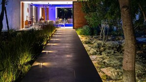 Une maison moderne avec un long chemin droit menant à une entrée bien éclairée.