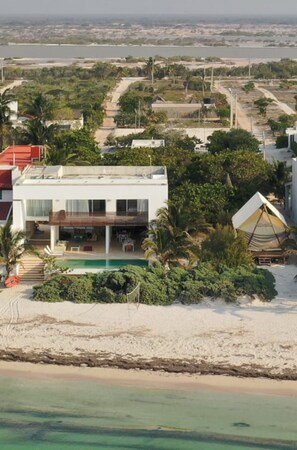 A modern beachfront property with a swimming pool, a covered patio, and a view of the ocean. - Beachfront Villa - Padel & Glamping at LAHOS (Chicxulub)