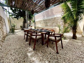 Un espace de restauration en plein air, avec une table et des chaises, entouré de galets et de plantes.