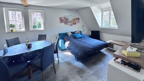 Una camera da letto moderna mansardata con un letto grande, un tavolo da pranzo e una televisione.
