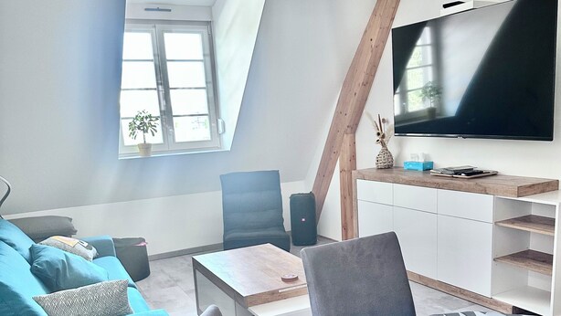 Un soggiorno moderno con una grande TV a schermo piatto, un divano blu e un tavolino da caffè decorato.