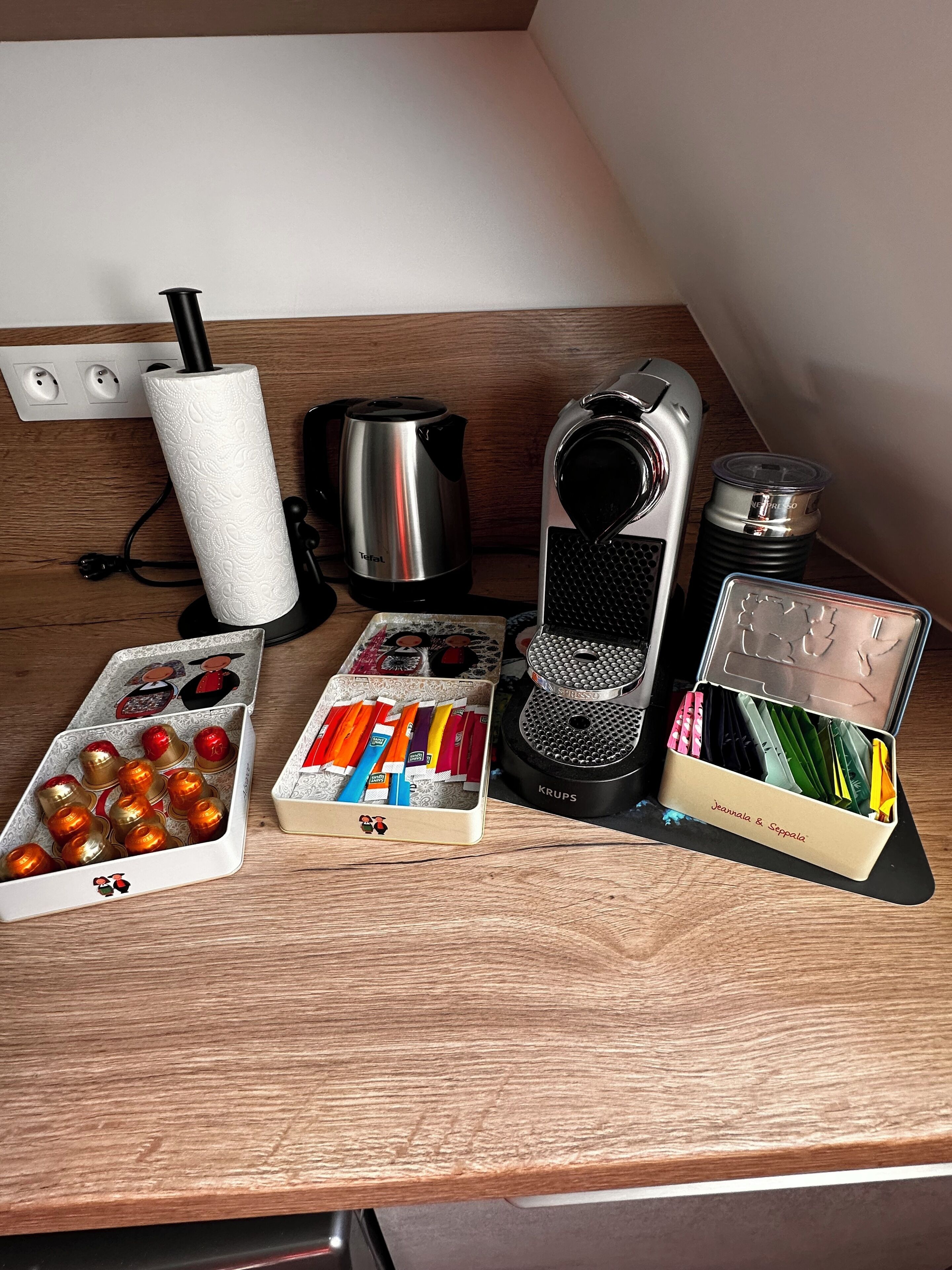 Una encimera de cocina con una tetera, una cafetera y termos de bolsitas de té.